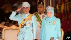 Malaysia's King Sultan Abdullah Sultan Ahmad Shah salutes next to Queen Tunku Azizah Aminah Maimunah and Prime Minister Mahathir Mohamad, center, during his welcome ceremony at Parliament House in Kuala Lumpur, Jan. 31, 2019. 
