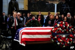 Former Sen. Bob Dole salutes the flag-draped casket containing the remains of former President George H.W. Bush as he lies in state at the U.S. Capitol in Washington, Dec. 4, 2018.