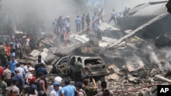 Para petugas pemadam kebakaran dan militer memeriksa lokasi jatuhnya pesawat Air Force Hercules C-130 di Medan, Sumatera Utara (30/6). (AP Photo/Gilbert Manullang).