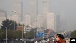 زن چینی در مرکز پکن که برای حفاظت خود از آلودگی هوا ماسک زده است - چین جزو ۳ کشوری است که در رأس جدول بیشترین تولید کنندگان دی اکسید کربن قرار دارند. دو کشور دیگر آمریکا و هند هستند. 
