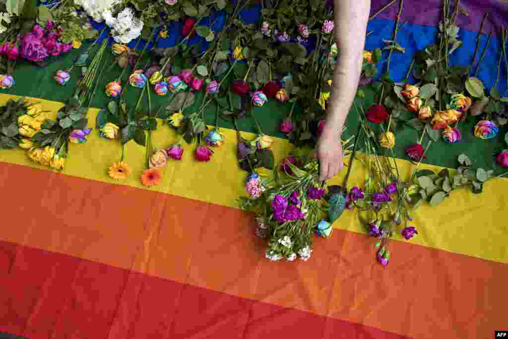 Demonstrators lay roses on a rainbow flag as they protest an alleged crackdown on gay men in Chechnya, outside the Russian Embassy in London.