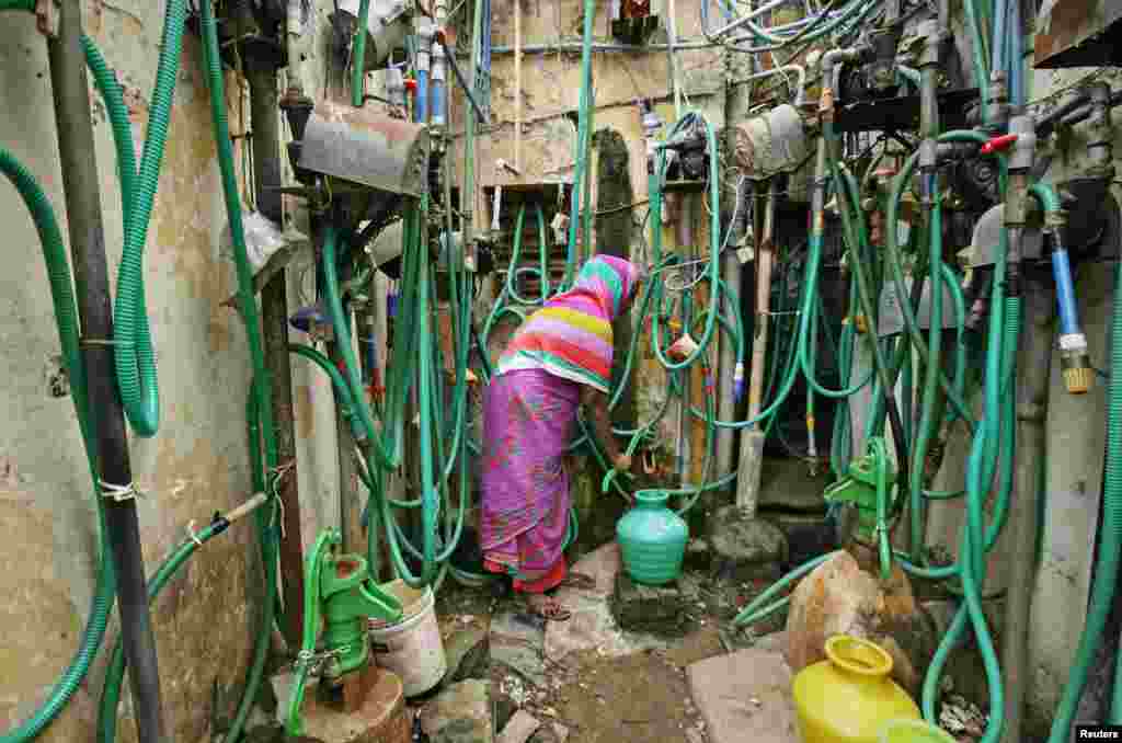 A woman uses a hand pump to fill up a container with drinking water in Chennai, India.