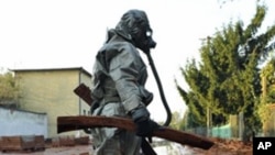 A Hungarian soldier, wearing chemical protection gear, cleans a street flooded by toxic waste in the town of Devecser, 05 Oct 2010