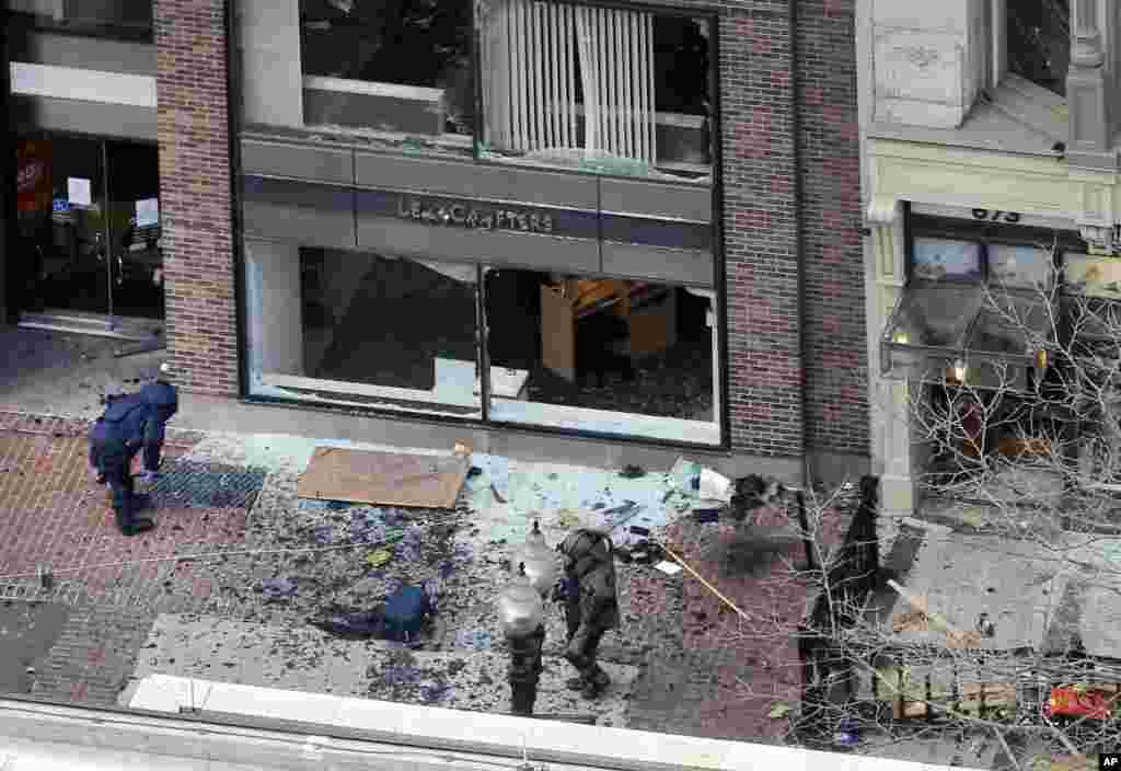 One of the blast sites on Boylston Street near the finish line of the 2013 Boston Marathon is investigated by two people in protective suits in the wake of two blasts, April 15, 2013.