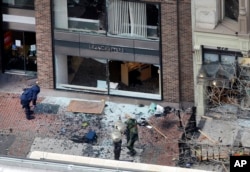 FILE - One of the blast sites on Boylston Street near the finish line of the 2013 Boston Marathon is investigated by two people in protective suits in the wake of two blasts, April 15, 2013.
