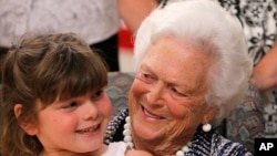 FILE - Mia Trumble, 7, sits on Barbara Bush's lap after the former first lady spoke at ceremony for Literacy Maine, June 15, 2011, in Biddeford, Maine. 