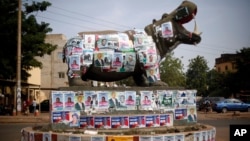 A statue of a hippopotamus is covered with election posters at a traffic circle in Bamako, Mali, Nov. 19, 2013.