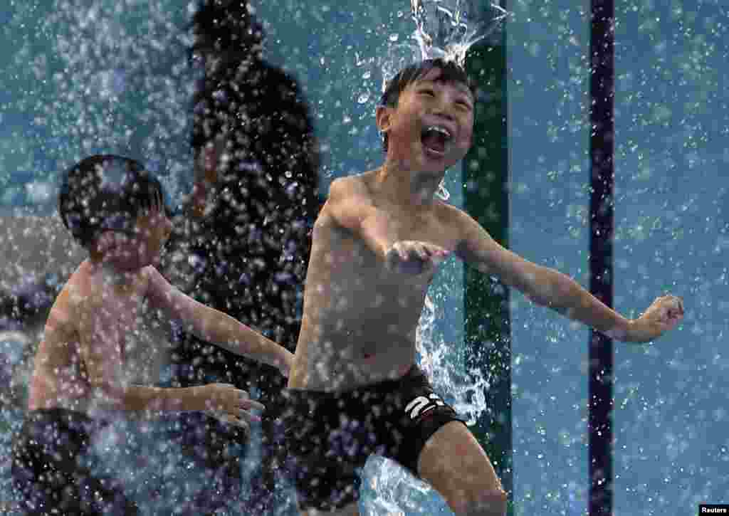 Anak-anak bermain air di sebuah taman di hari yang panas di Singapura. Singapura dan Malaysia berkutat dengan cuaca terkering dalam sejarah, memaksa kota negara kecil itu meningkatkan pasokan air daur ulang sementara tetangganya menjatah cadangan di tengah-tengah gangguan pertanian dan perikanan.