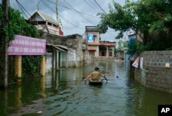 A man paddles a boat through flooded village in Chuong My district, Hanoi, Vietnam, July 31, 2018.