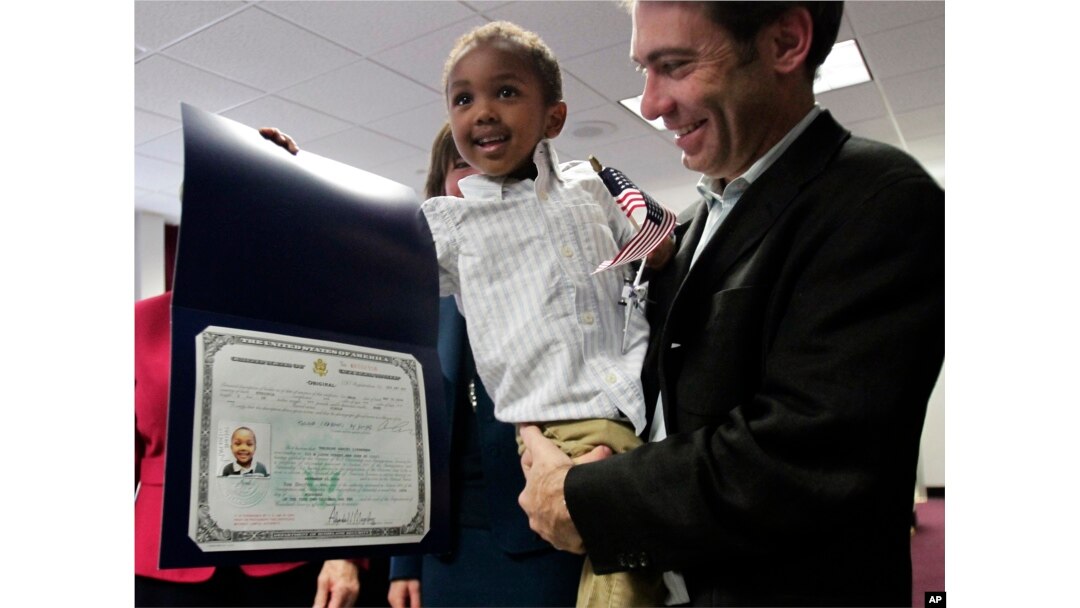 FILE - Aaron Lieberman holds his son Theodore, 2, adopted from Ethiopia, as he shows his citizenship certificate, during the U.S. Citizenship and Immigration Services (USCIS) Adoption Day ceremony on Nov. 18, 2010, in New York.