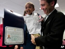 FILE - Aaron Lieberman holds his son Theodore, 2, adopted from Ethiopia, as he shows his citizenship certificate, during the U.S. Citizenship and Immigration Services (USCIS) Adoption Day ceremony on Nov. 18, 2010, in New York.