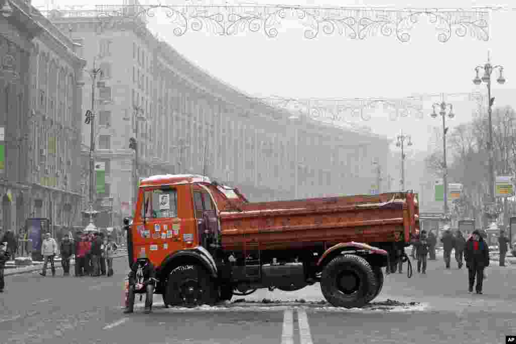 A Pro-European Union activist dressed in a military helmet sits on the side of a truck with flat tires used as a barricade on the main street Khreschatyk during a rally in Kyiv, Dec. 12, 2013.