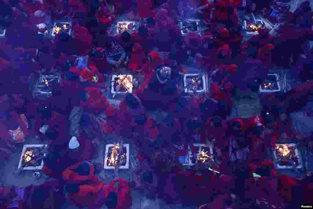 Hindu women sit around fires to warm themselves up before taking a holy bath at Saali River during the first day of the Swasthani Brata Katha festival at Sankhu in Kathmandu, Nepal.