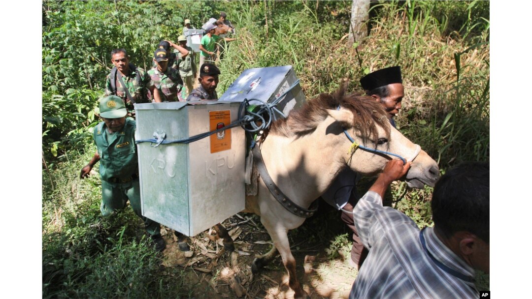 Electoral workers, escorted by police officers and soldiers, use horses to transport ballot boxes to polling stations in remote areas in Tlogosari, East Java, Indonesia, July 8, 2014.