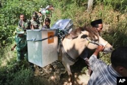 Electoral workers, escorted by police officers and soldiers, use horses to transport ballot boxes to polling stations in remote areas in Tlogosari, East Java, Indonesia, July 8, 2014.