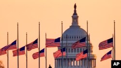 Lowered to half-staff in honor of former Senate Majority Leader Bob Dole of Kansas, flags fly in the breeze at sunrise on the National Mall with the U.S. Capitol in the background, Dec. 6, 2021.