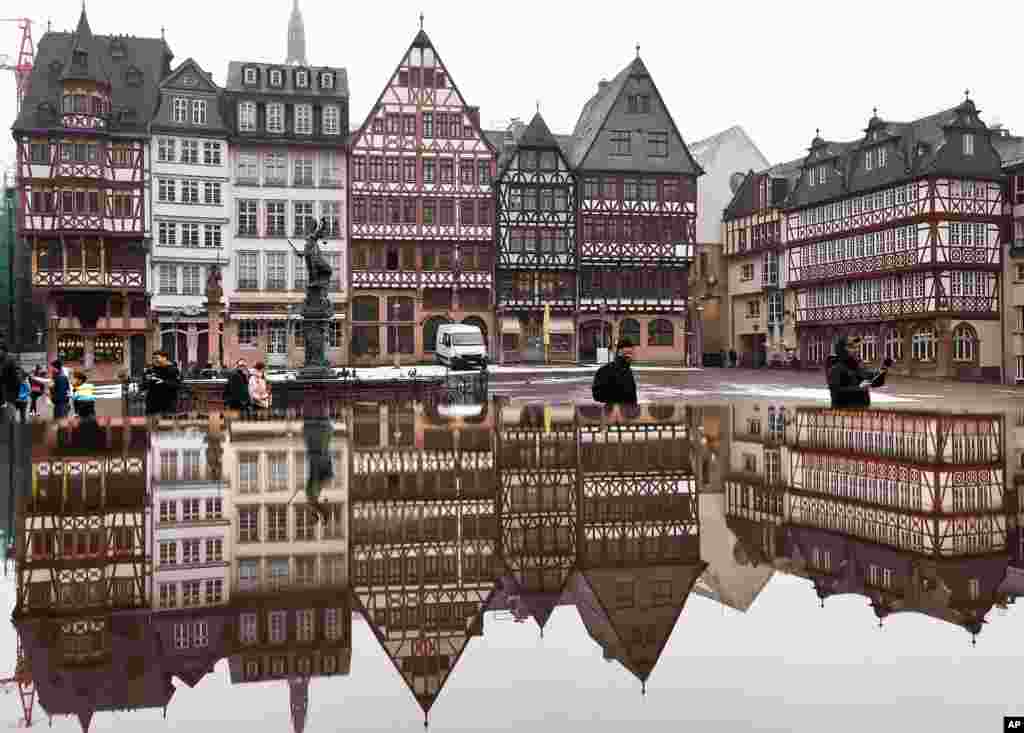 The timber-frame houses at the Roemerberg square are reflected in water in Frankfurt, central Germany.