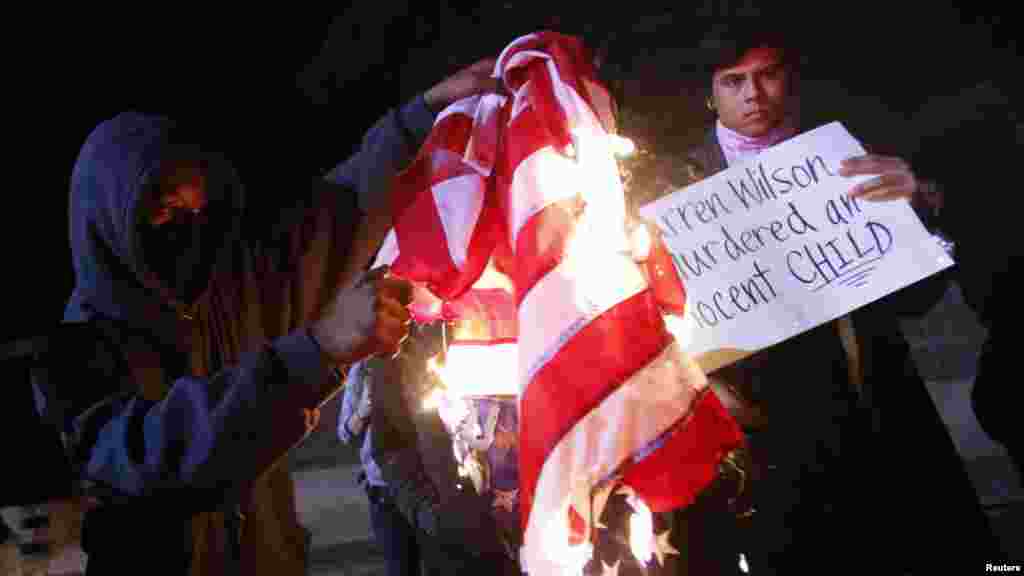 A protester burns an American flag on Highway 580 during a demonstration following the grand jury decision in the Ferguson, Missouri shooting of Michael Brown, in Oakland, California, November 24, 2014.