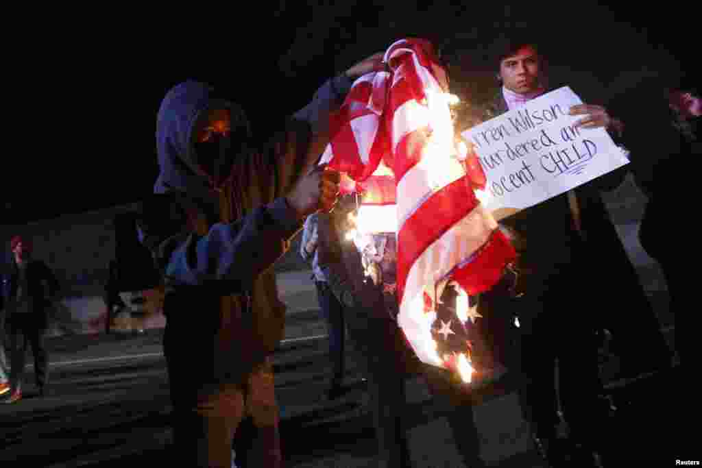 A protester burns an American flag on Highway 580 during a demonstration following the grand jury decision in the shooting of Michael Brown, in Oakland, California, Nov. 24, 2014.