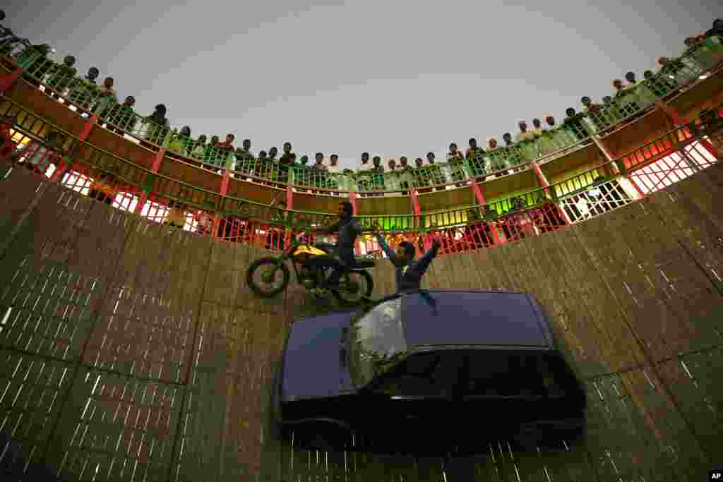 인도 뭄바이 시에서 열린 마힘 전시회에서 관람객들이 벽을 타고 자동차와 오토바이를 운전하는 스턴트를 구경하고 있다.