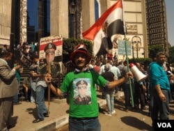 A government supporter holds the Egyptian flag and a poster of President Abdel-Fattah el-Sissi at a mostly anti-government protest in downtown Cairo, April 15, 2016. (VOA/H. Elrasam)