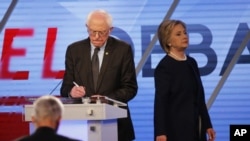 Democratic presidential candidate, Hillary Clinton enters the stage after a break as Democratic presidential candidate, Sen. Bernie Sanders, I-Vt, makes notes, during the Univision, Washington Post Democratic presidential debate at Miami-Dade College, W