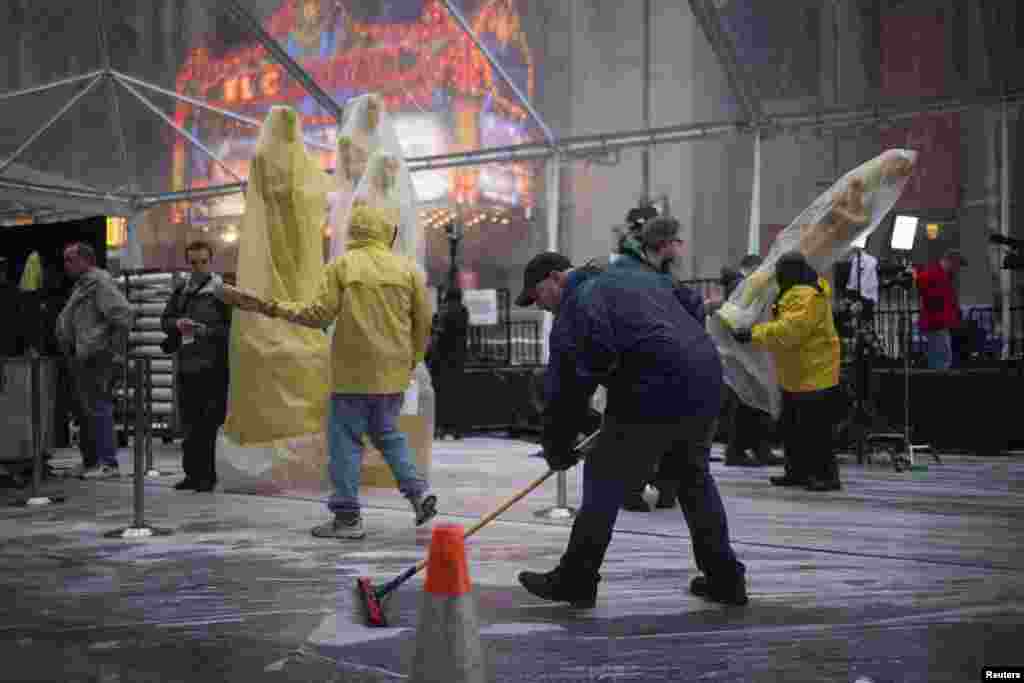 Oscars statues are seen in the background as a man clears rain water from the red carpet ahead of the 86th Academy Awards in Hollywood, California, March 1, 2014.&nbsp;