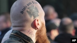 FILE - A right-wing demonstrator with a tattoo reading: 'Proud and Free' marches in Cologne, Germany, Jan. 9, 2016.