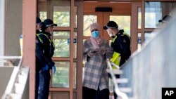 Polisi memberikan keterangan kepada seorang perempuan di kompleks apartemen yang di-lockdown sebagai upaya mengurangi penyebaran Covid-19 di Melbourne, Australia, Senin, 6 Juli 2020.