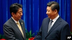 中國國家主席習近平（右）和日本首相安培晉三（左）去年在亞太經合組織會議上握手。
