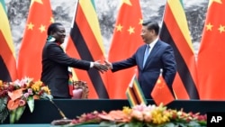 Zimbabwean President Emmerson Mnangagwa, left, shakes hands with Chinese President Xi Jinping as they pose for the media after a signing ceremony at the Great Hall of the People in Beijing, China, April 3, 2018.