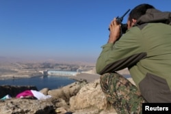 A fighter from the Syrian Democratic Forces takes a position atop Mount Annan overlooking the Tishrin Dam, after they captured it from Islamic State militants, south of Kobani, Syria, Dec. 27, 2015.