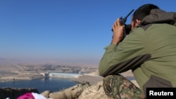 A fighter from the Syrian Democratic Forces takes a position atop Mount Annan overlooking the Tishrin Dam, after they captured it from Islamic State militants, south of Kobani, Syria, Dec. 27, 2015.