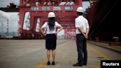 FILE - Employees stand next to a container ship at Ningbo port in Ningbo, Zhejiang province, June 21, 2012. 