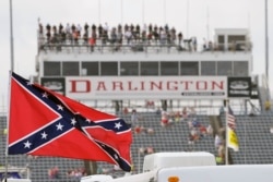 FILE - In this Sept. 5, 2015, file photo, a Confederate flag flies before a NASCAR race at Darlington Raceway in Darlington, S.C. Bubba Wallace, the only African-American driver in NASCAR, calls for a ban on the Confederate flag in the sport that is deepl