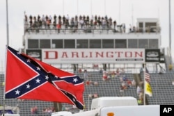 FILE - In this Sept. 5, 2015, file photo, a Confederate flag flies before a NASCAR race at Darlington Raceway in Darlington, S.C. Bubba Wallace, the only African-American driver in NASCAR, calls for a ban on the Confederate flag in the sport that is deepl