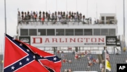 FILE - In this Sept. 5, 2015, file photo, a Confederate flag flies before a NASCAR race at Darlington Raceway in Darlington, S.C. Bubba Wallace, the only African-American driver in NASCAR, calls for a ban on the Confederate flag in the sport that is deepl