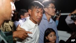 Two former Radio Free Asia reporters Oun Chhin, center, and Yeang Sothearin, right, hold together as they walk outside the main prison of Prey Sar at the outskirt of Phnom Penh, Cambodia, Tuesday, Aug. 21, 2018. Two Cambodian journalists who had worked for U.S.-funded Radio Free Asia and are charged with espionage have been released on bail, a day after a pardon freed four land rights activists from prison. (AP Photo/Heng Sinith)