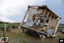 Juan Negron (der.) se prepara para conectar un generador frente a lo que queda de su propiedad tras el paso del huracán Irma. Isla de Culebra, Puerto Rico. Sept. 7, 2017.