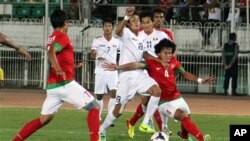 အင်ဒိုနီးရှားက Rizky Ahmad Sanjaya Pellu (ယာ) နဲ့ ကျော်မင်းဦး (လယ်) တို့အား ၂၇ ကြိမ်မြောက် အရှေ့တောင်အာရှ ဘောလုံးပြိုင်ပွဲ၊ သုဝဏ္ဏကွင်းမှာ တွေ့ရစဉ်။ (ဒီဇင်ဘာ ၁၆၊ ၂၀၁၃)