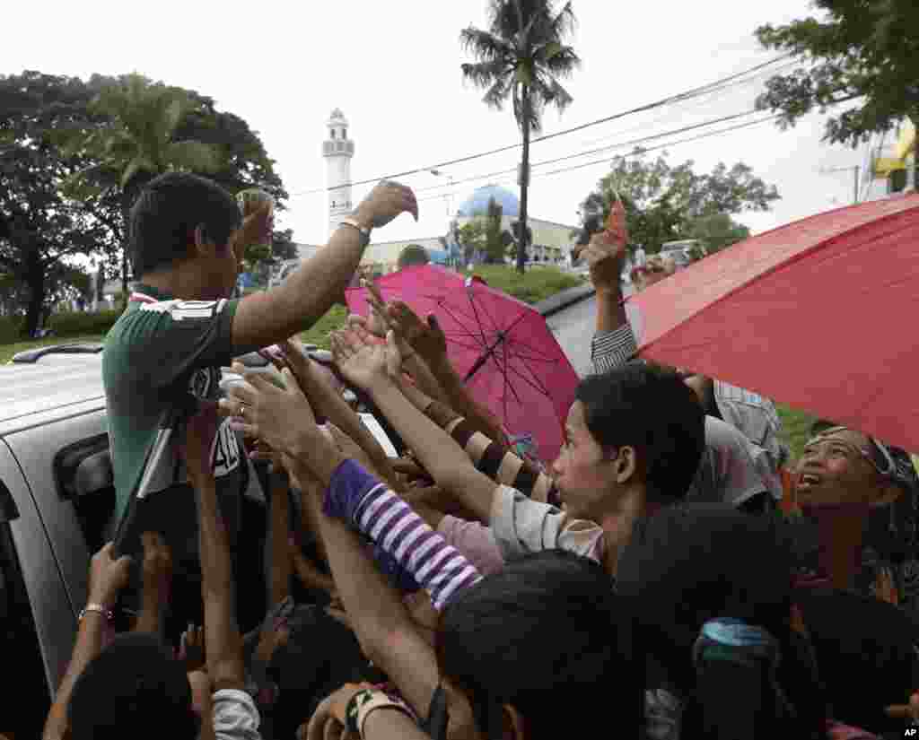 A Philippine Muslim hands out cash to children following prayers at the Blue Mosque (background) in Taguig city, east of Manila, Philippines, October 26, 2012. 