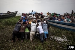 Internally displaced Congolese push a boat out, as its sets off to escape over Lake Albert to Uganda, March 05, 2018, in Tchomia, DRC.