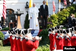 U.S. President Barack Obama, right, and Pope Francis watch onstage as the "Old Guard" fife and drum corps marches past during an official welcome ceremony on the South Lawn at the White House in Washington, Sept. 23, 2015.