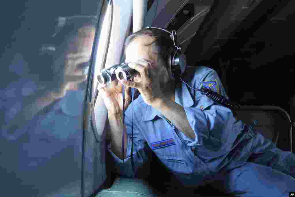 A Vietnamese Air Force colonel uses binoculars on board a flying aircraft during a mission to search for the missing Malaysia Airlines flight MH370 in the Gulf of Thailand, March 13, 2014. 