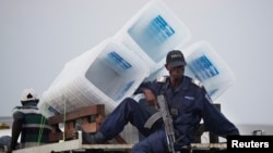FILE - A policeman sits atop a minibus carrying empty ballot boxes to a central counting center in Democratic Republic of Congo's capital Kinshasa.