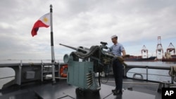 FILE - A member of the Philippine Navy demonstrates one of the guns on board the BRP Gregorio Del Pilar (PF15) warship at Manila's pier, amid tensions with China over the disputed Spratly Islands in the South China Sea, Dec. 17, 2014. 