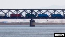 FILE - Trucks drive on the Friendship Bridge over the Yalu River, which connects North Korea's Sinuiju to China's Dandong, April 11, 2013.