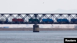 FILE - Trucks drive on the Friendship Bridge over the Yalu River which connects North Korea's Sinuiju to China's Dandong, April 11, 2013.