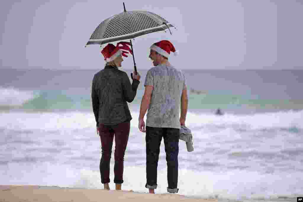 Scott Relf and his girlfriend Lauren Harris laugh as they stand in the rain on Bondi Beach to celebrate Christmas Day in Sydney, Dec. 25, 2013.