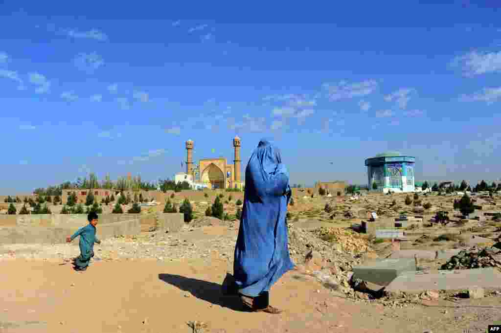 A burqa-clad Afghan woman walks near a cemetery in Herat province, Afghanistan.